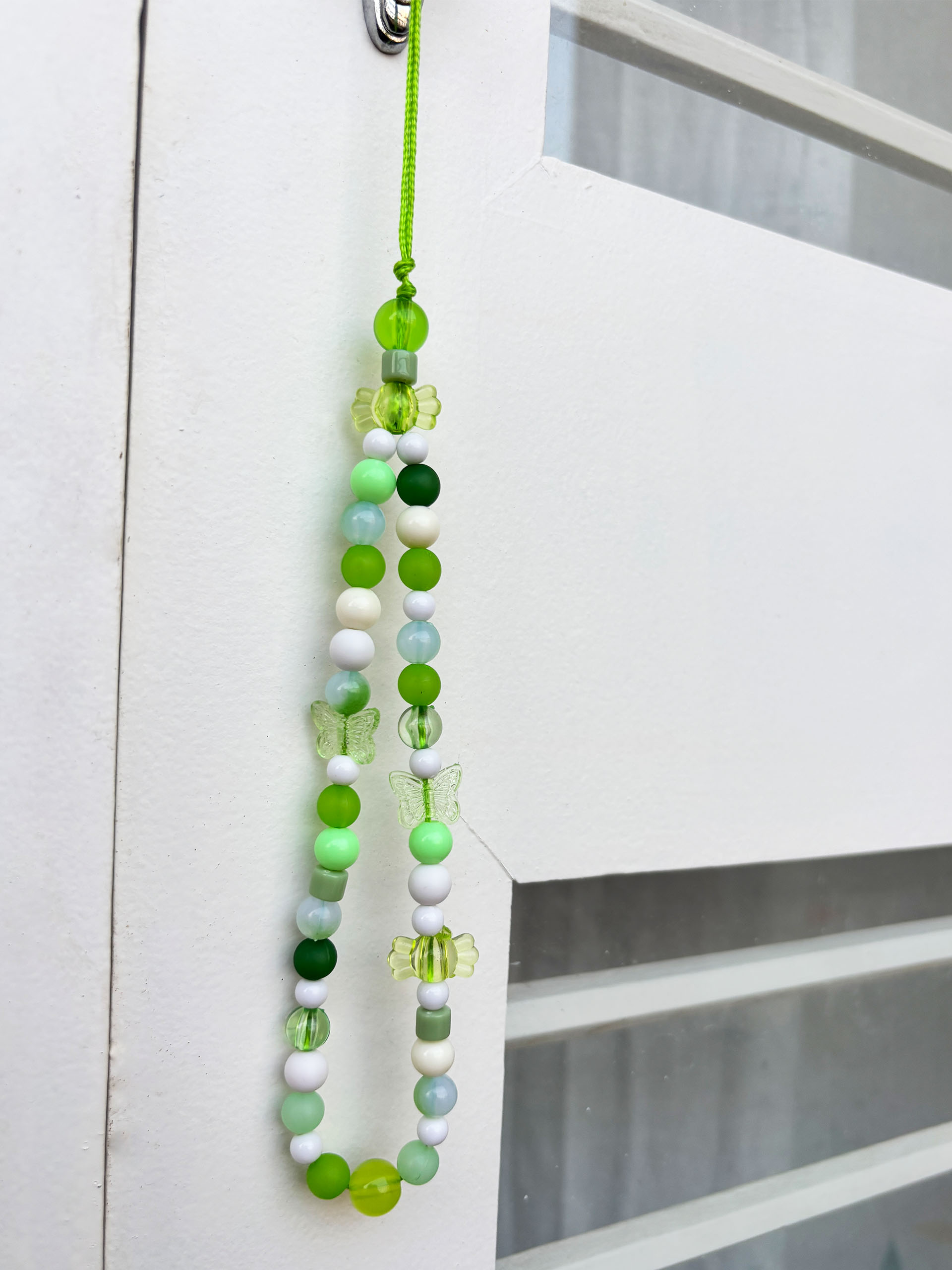 Fresh Meadow Beaded Charm - Inspired by lush greens and gentle garden vibes, this beaded charm strap brings together calming tones and playful details in the most refreshing way. With a mix of glossy beads, tiny florals, and delicate butterfly accents, it feels like a soft breeze from a blooming meadow.