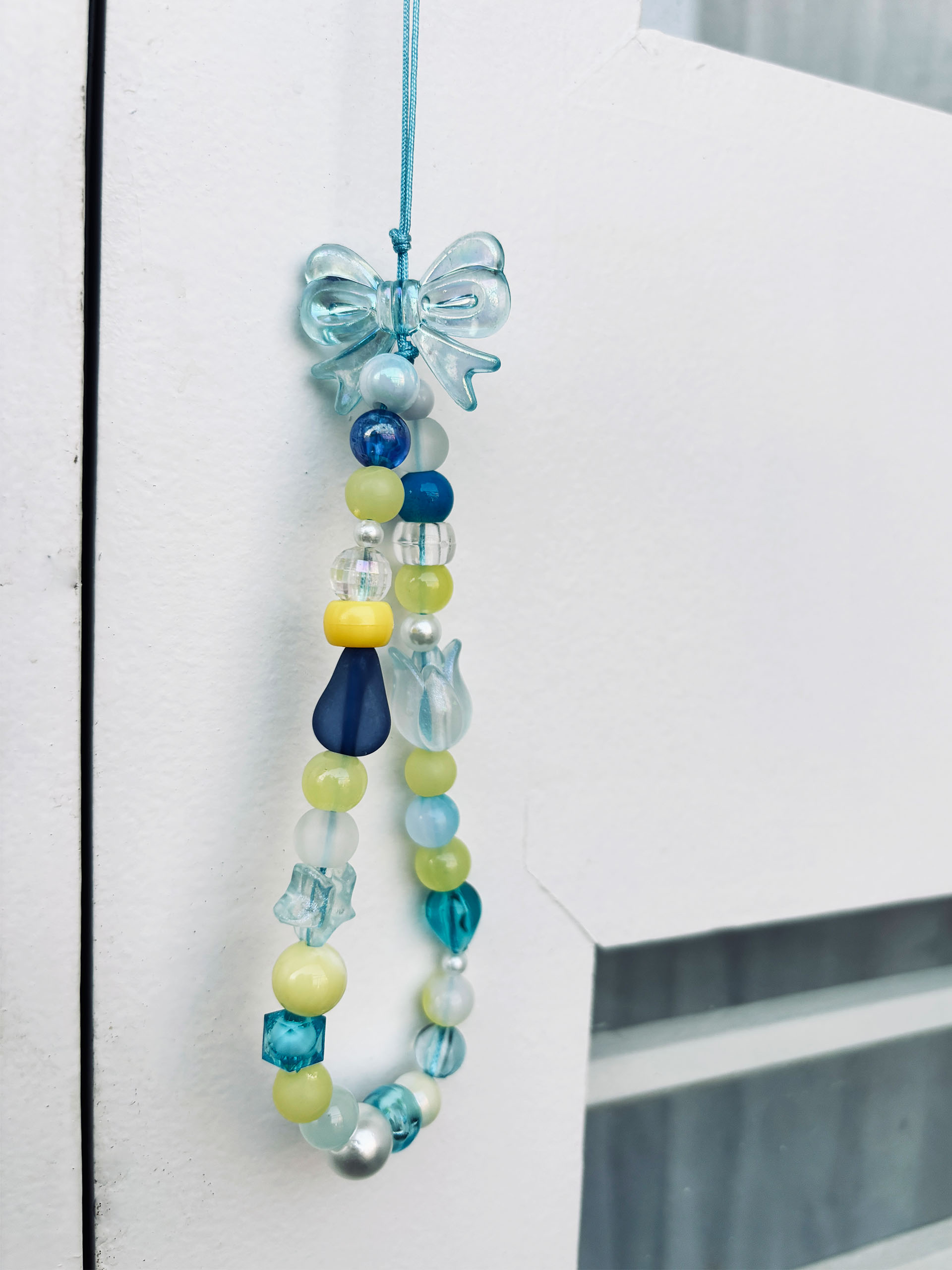 Ocean Dream Beaded Charm - Inspired by cool ocean tones and sunny skies, this beaded charm strap brings together a playful mix of shapes, colors, and textures. From glossy pearls and tiny flowers to stars and droplets, every bead adds its own little story—creating a charm that feels lively, fresh, and full of personality.