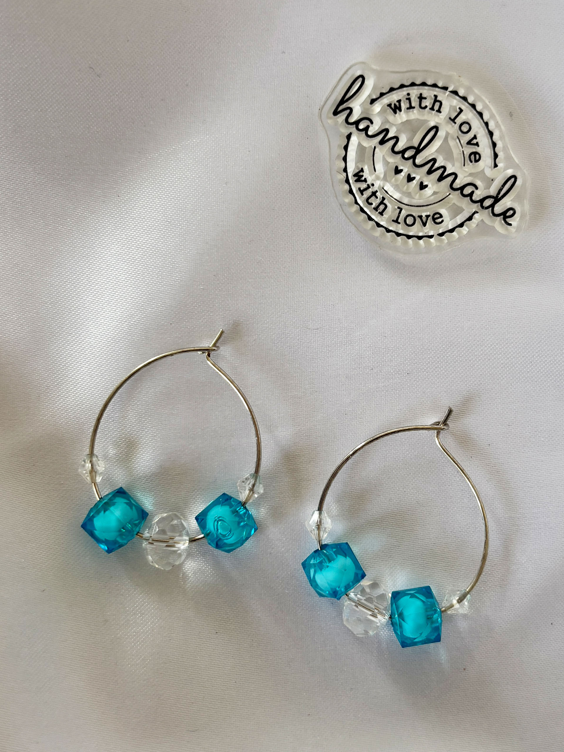 Aqua Sparkle Hoop Earrings - Fresh, minimal, and subtly sparkly, these aqua hoop earrings are designed to add a clean yet eye-catching touch to your look. Featuring translucent teal cube beads paired with clear crystal accents, they create a beautiful balance of color and shine.