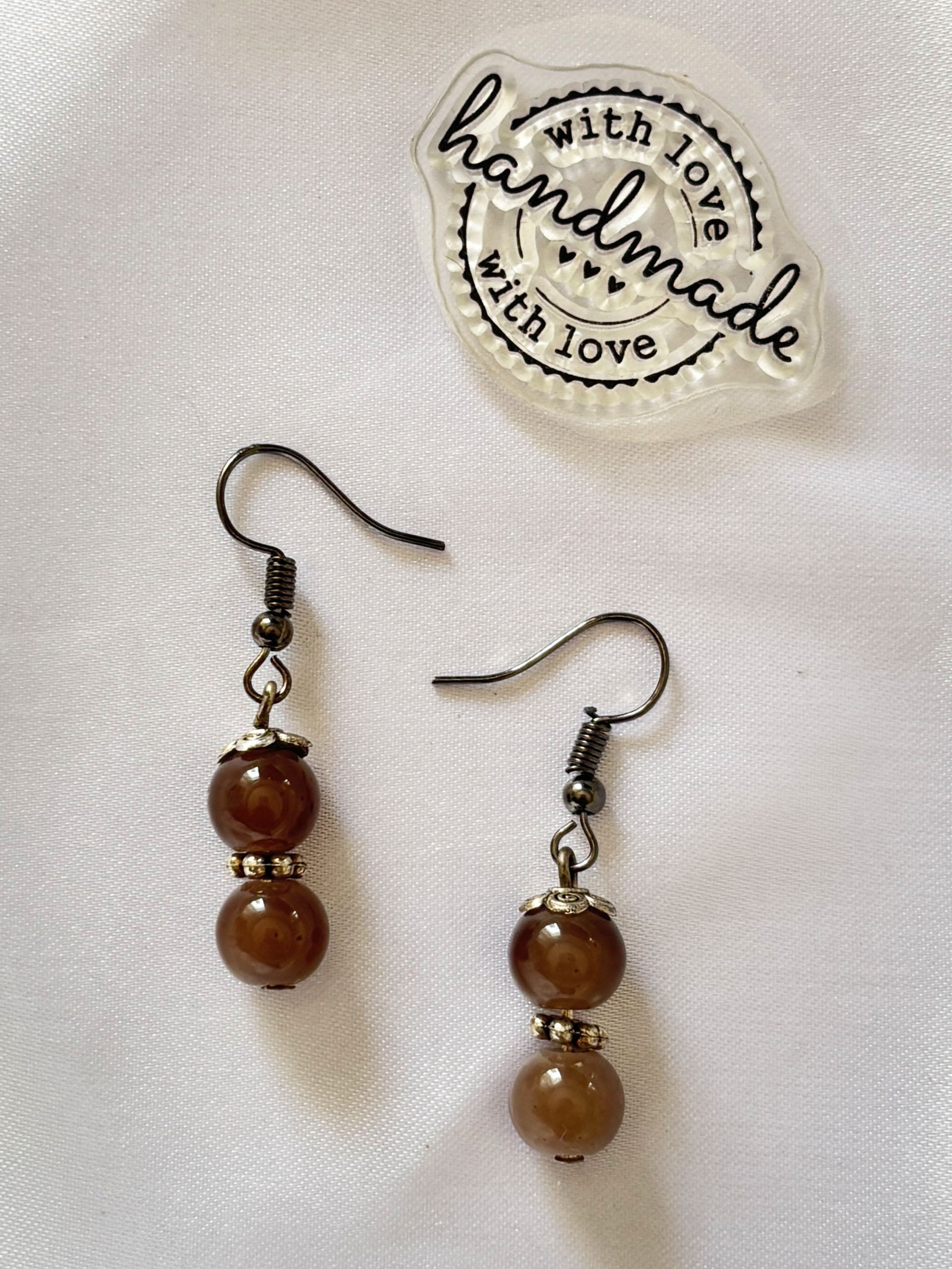 Caramel Charm Dangles - Warm, earthy, and effortlessly elegant, these brown bead earrings bring a grounded and timeless charm to your look. Featuring rich mocha-toned glossy beads paired with subtle metallic accents, they create a soft, neutral aesthetic that complements any outfit.