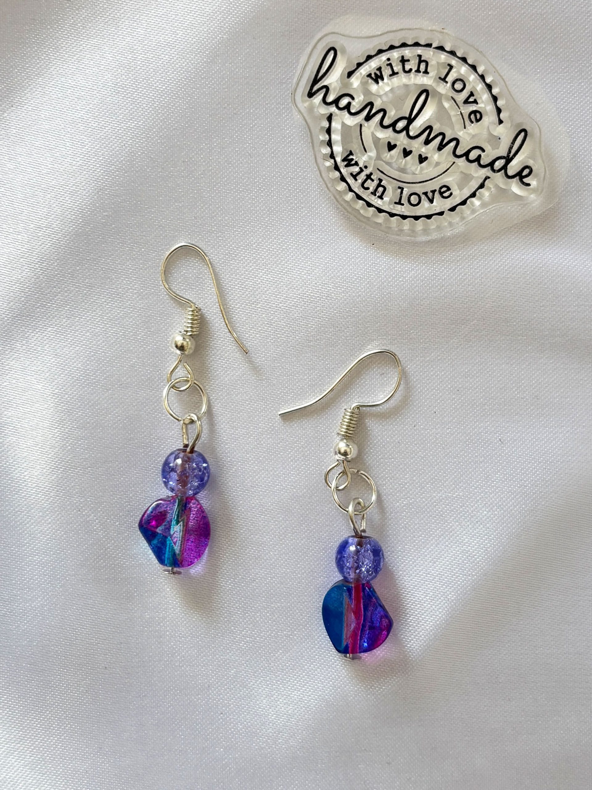 Galaxy Glaze Dangles - Bold, playful, and full of personality, these statement drop earrings are made to stand out. Featuring a striking mix of deep blues, electric pinks, and shimmering purples, each piece captures a dreamy, almost galaxy-like swirl of color.