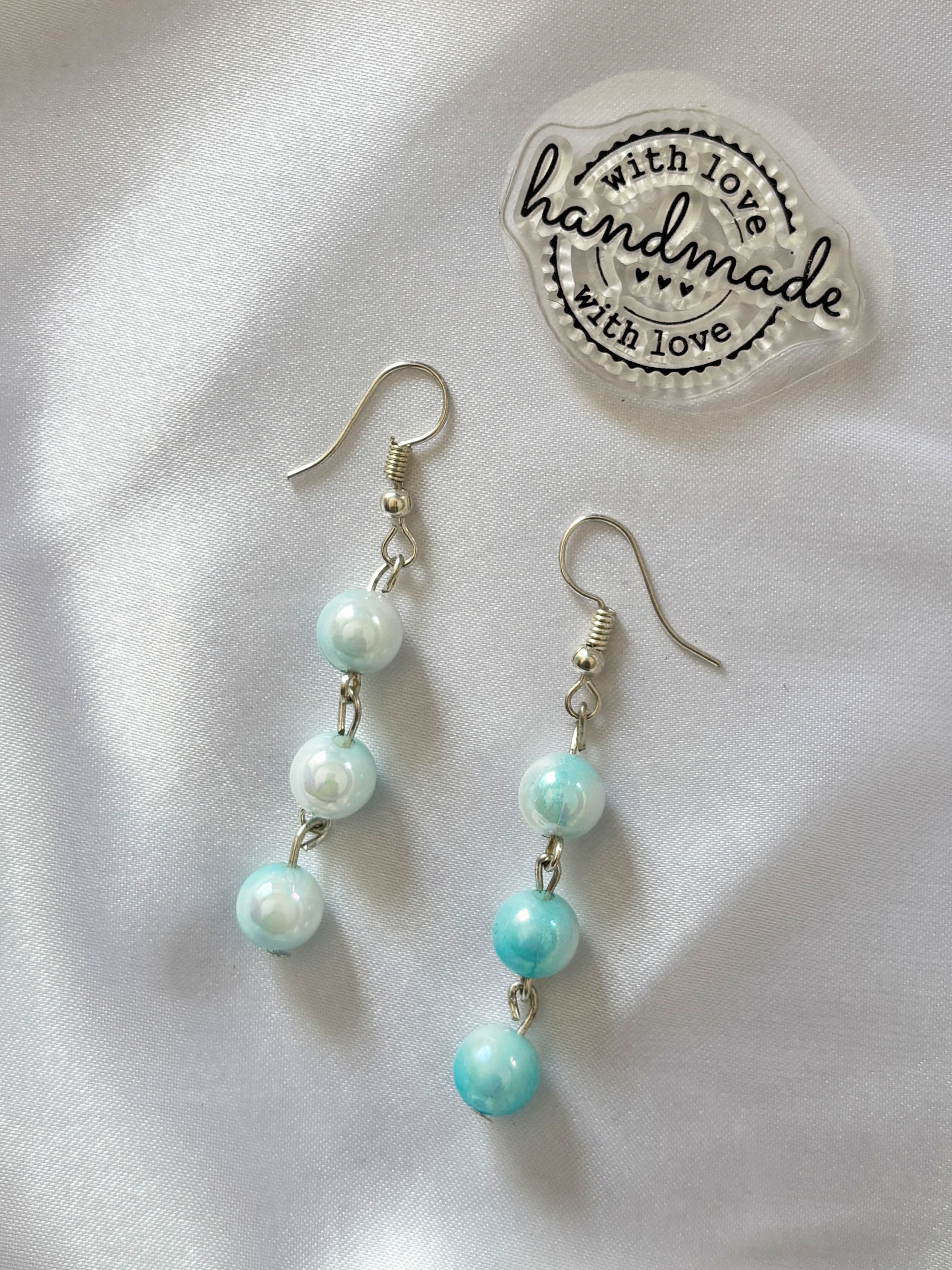 Seafoam Dream Drop Earrings - Bring a soft splash of elegance to your look with these dreamy aqua-toned drop earrings. Designed with a delicate cascade of glossy beads, each piece reflects light beautifully—giving off a subtle shimmer that feels both fresh and feminine.