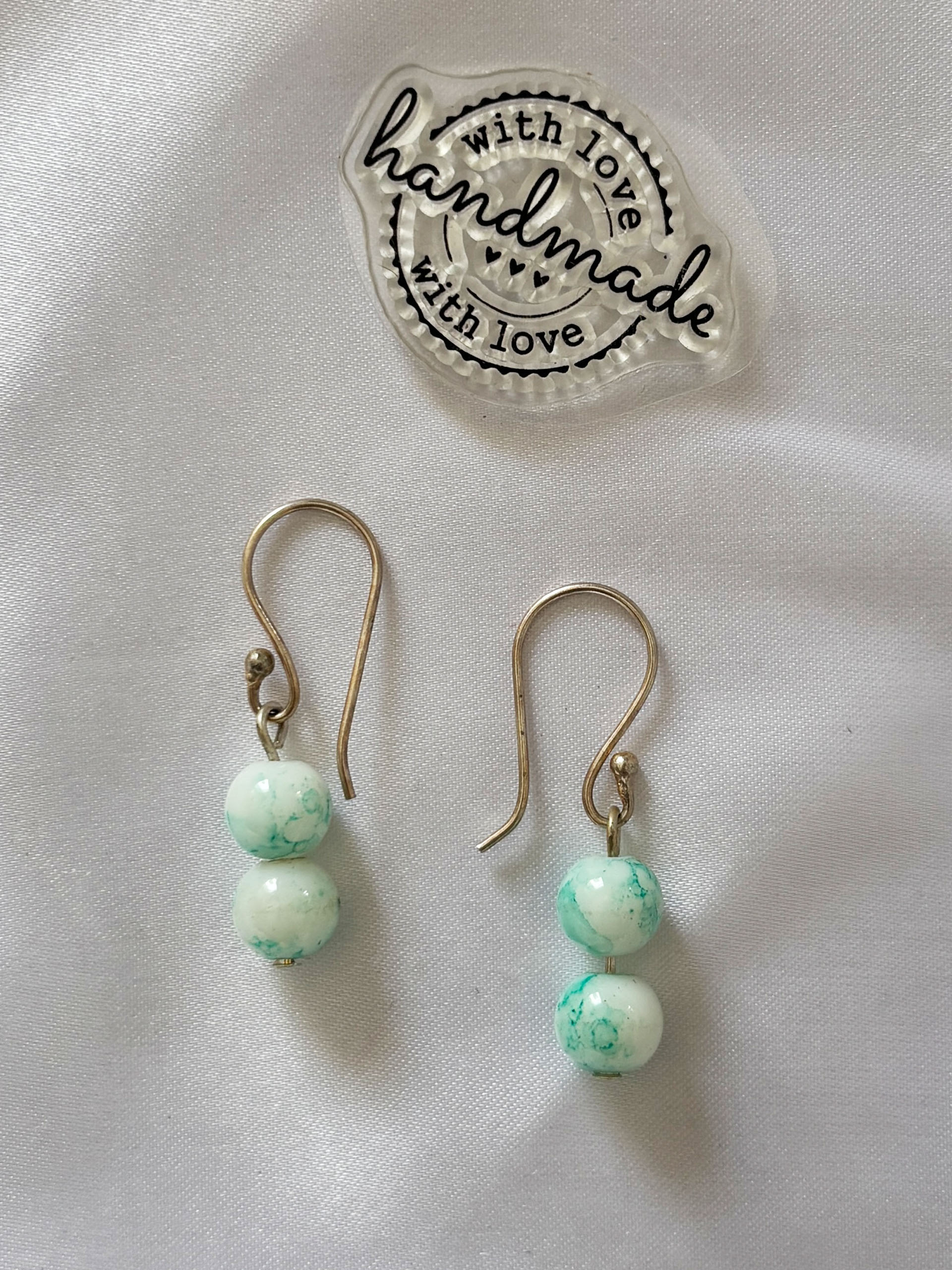 Soft Sage Marble Drops - Subtle, soothing, and effortlessly elegant, these double bead drop earrings are designed for lovers of minimal beauty. Featuring soft mint and creamy white marbled beads, each piece carries a unique pattern, making every pair one of a kind.