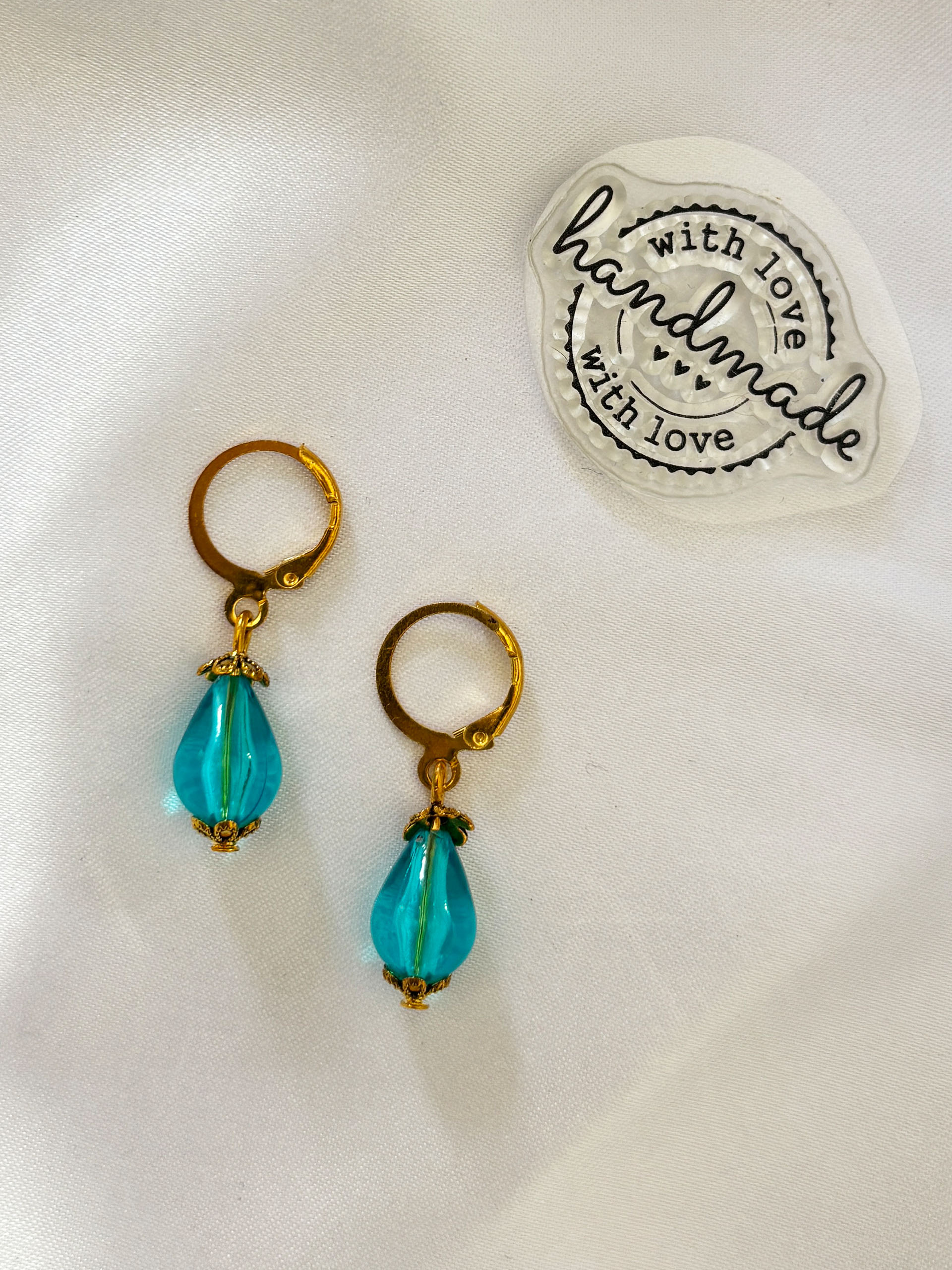 Teal Glow Dangle Earrings - Elegant, minimal, and effortlessly eye-catching, these aqua drop earrings bring a refreshing pop of color to your look. Featuring translucent teal teardrop beads paired with warm gold-toned hoops, they create a perfect balance of simplicity and charm.